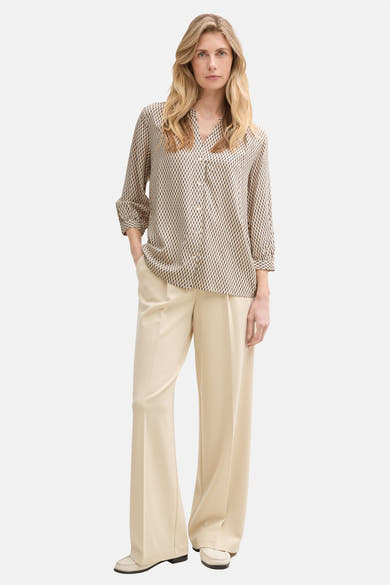 Chemisier à manches longues beige de Tom Tailor, avec un motif géométrique noir, porté avec un pantalon beige évasé.