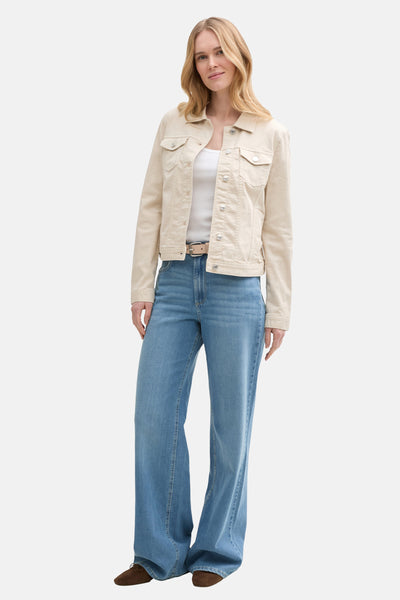 Beige spijkerjasje van Tom Tailor gedragen met een witte tanktop en een blauwe flared jeans.