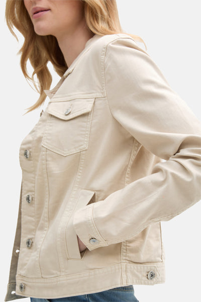 Veste en jean beige de Tom Tailor, avec poche poitrine et boutonnage métallique, portée sur un jean bleu.
