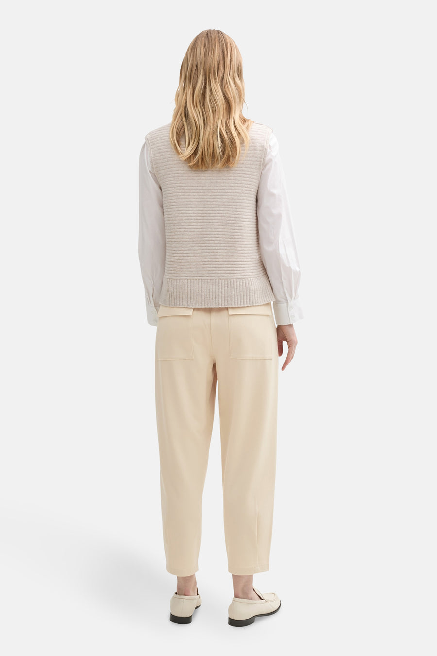 Chino 7/8 beige de Tom Tailor, avec poches plaquées à l'arrière, porté avec un gilet sans manches.
