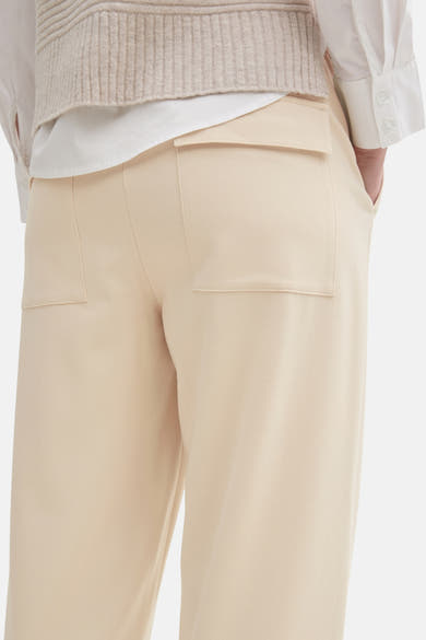 Beige 7/8 chino broek van Tom Tailor met opgestikte achterzakken, gedragen met een mouwloze trui.