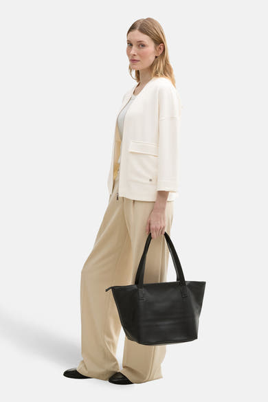 Gilet blanc par Tom Tailor, porté ouvert avec pantalon beige ample et sac noir en cuir.
