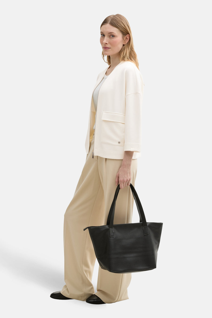 Gilet blanc par Tom Tailor, porté ouvert avec pantalon beige ample et sac noir en cuir.