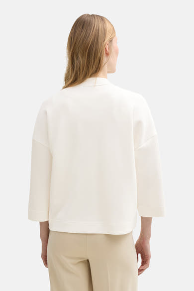 Witte Tom Tailor sweatshirt met driekwartmouwen, gedragen met een beige broek.