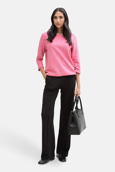 Roze rondehals sweatshirt van Tom Tailor, gedragen met een zwarte broek en een leren handtas.