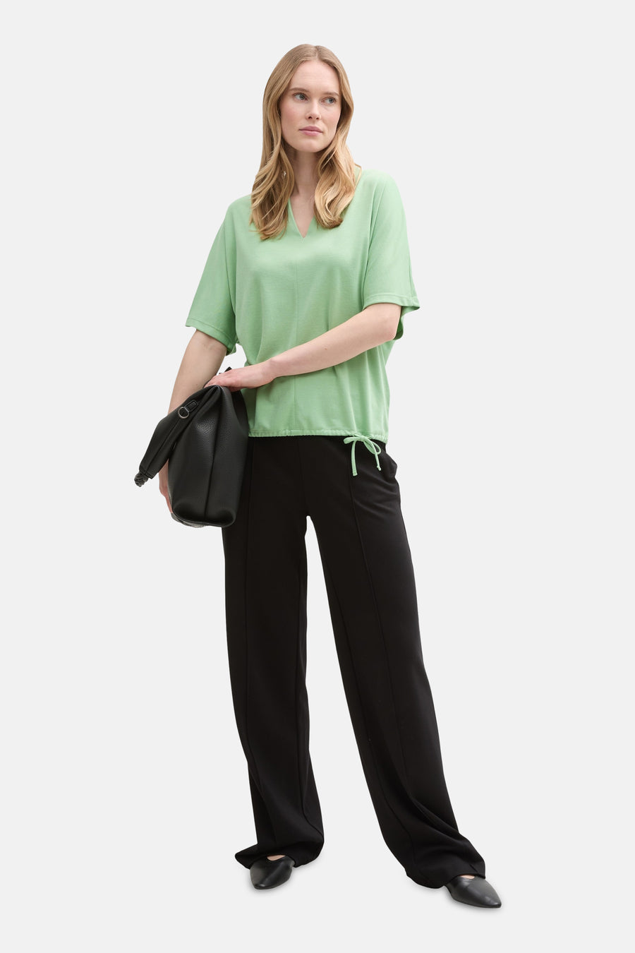 T-shirt vert à manches courtes de Tom Tailor, porté avec un pantalon noir et un sac à main.