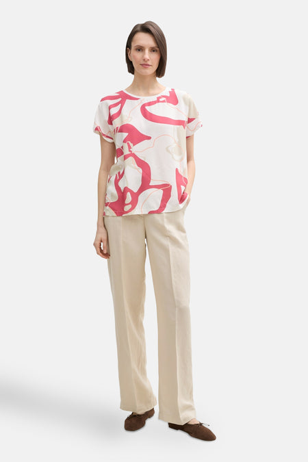 Blouse à manches courtes multicolore de Tom Tailor avec un motif abstrait rouge et pantalon beige.
