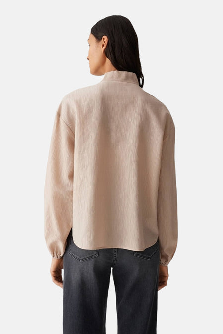 Beige blouse met lange mouwen van OPUS, getextureerd, met een opstaande kraag, gedragen met een verbleekte spijkerbroek.