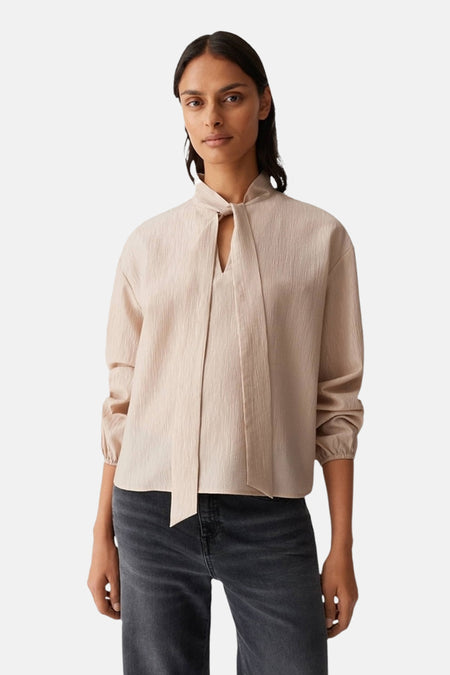 Beige blouse met lange mouwen van OPUS, met opstaande strikkraag en geplooide textuur, gedragen met een zwarte jeans.