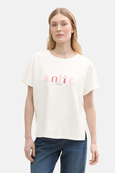 Ecru T-shirt met korte mouwen van Tom Tailor, versierd met een roze "sunshine" motief en gedragen met een spijkerbroek.