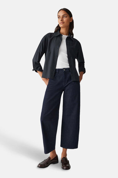 Chemise à manches longues bleue d'OPUS, portée ouverte sur un t-shirt blanc, avec un pantalon large en denim foncé.