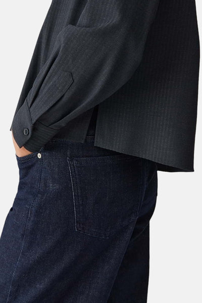 Chemise à manches longues bleue OPUS, détail de la manche avec bouton, portée avec un jean foncé.

