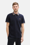 Donkerblauwe polo met korte mouwen van Tom Tailor, met strepen op de kraag en mouwen, gedragen met een marineblauwe broek en zwarte schoenen.