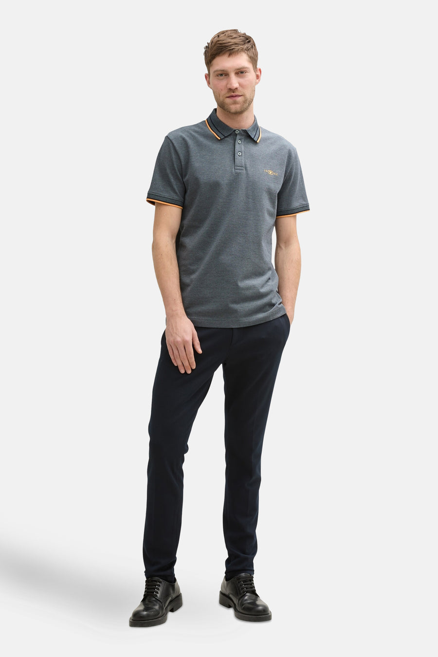 Polo bleu à manches courtes de Tom Tailor, avec col et manches contrastés orange, porté avec pantalon et chaussures noirs.