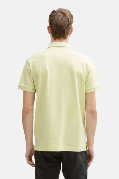 Polo à manches courtes vert de Tom Tailor, avec bordures blanches aux manches et col, porté avec un jean noir.