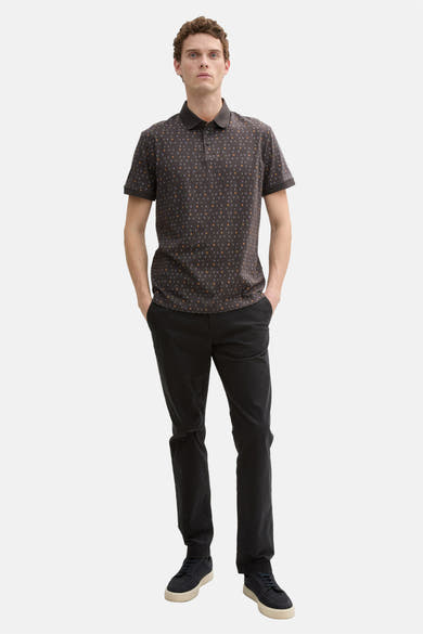 Grijze polo met korte mouwen van Tom Tailor, met discrete patronen, gedragen met een zwarte broek en bijpassende schoenen.