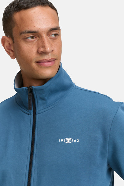 Gilet turquoise de Tom Tailor avec fermeture éclair noire et logo blanc.