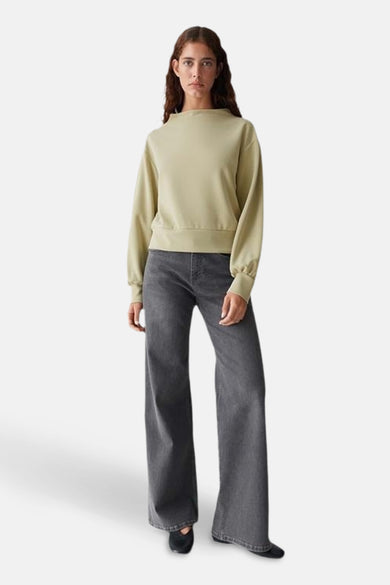 Sweat-shirt vert par OPUS, porté avec un jean gris ample et des chaussures noires.