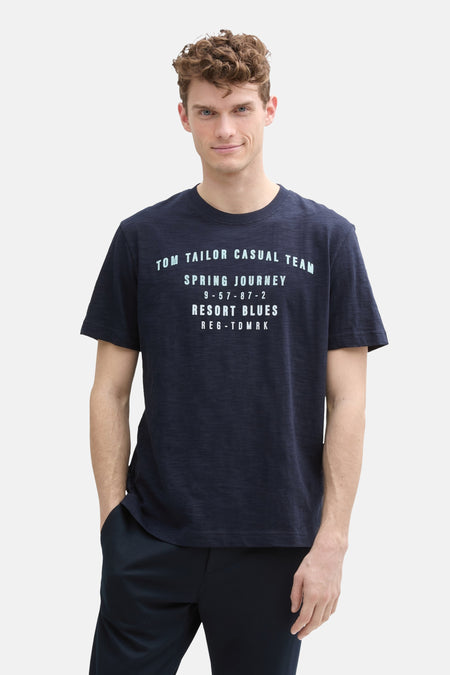 Donkerblauw T-shirt met korte mouwen van Tom Tailor, met opdruk op de voorkant, gedragen met een bijpassende broek.