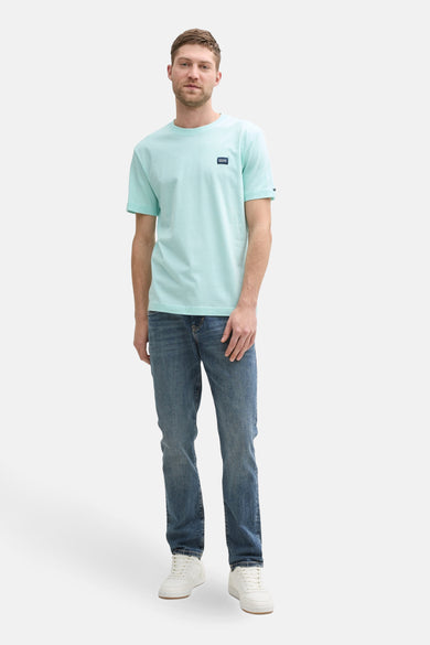 Turquoise T-shirt met korte mouwen van Tom Tailor, gedragen met een spijkerbroek en witte sneakers.