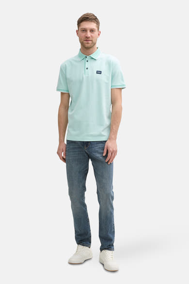 Mintgroen poloshirt met korte mouwen van Tom Tailor, met logo op de borst en gedragen met een spijkerbroek.