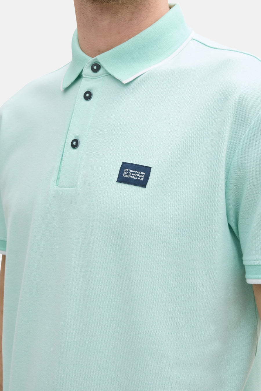 Groen poloshirt met korte mouwen van Tom Tailor, met zwarte knopen en marineblauwe logo.