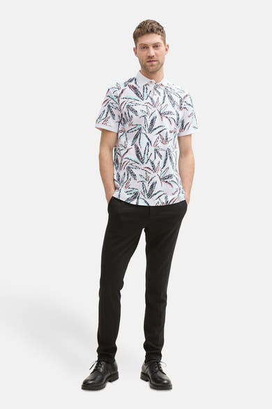 Polo multicolore à manches courtes de Tom Tailor, avec imprimé feuillage, porté avec un pantalon noir et des chaussures noires.