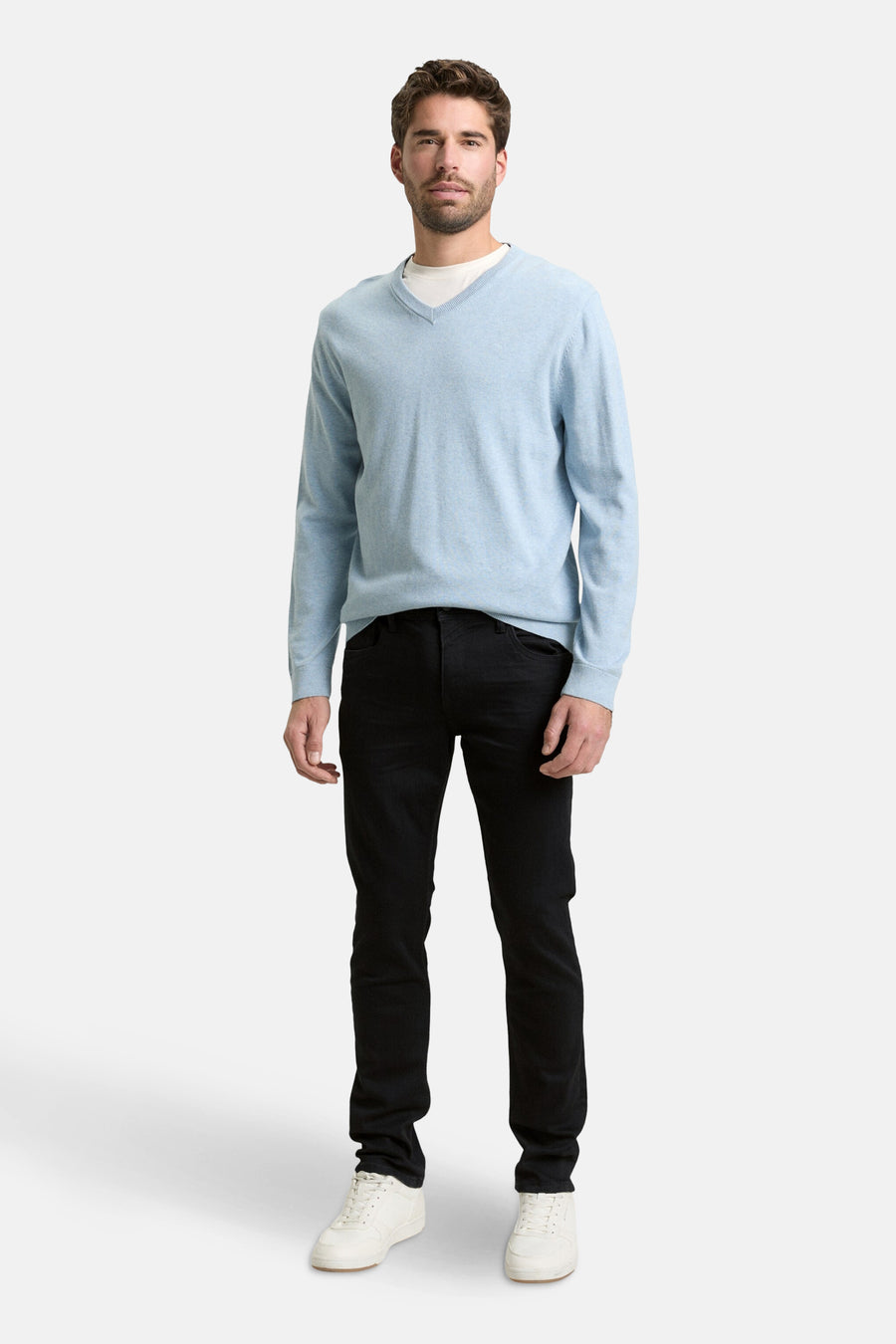 Zwarte rechte jeans van Tom Tailor, gedragen met een lichtblauwe trui en witte sneakers.