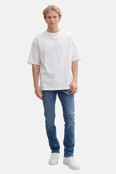 Rechte jeans in middinblauw denim van Tom Tailor, gedragen met een wit T-shirt en witte sneakers.