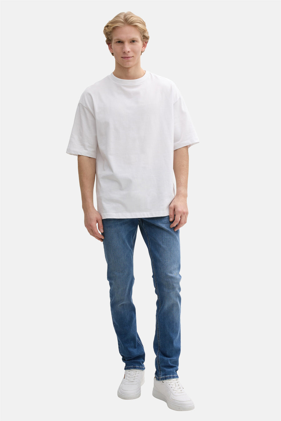 Rechte jeans in middinblauw denim van Tom Tailor, gedragen met een wit T-shirt en witte sneakers.