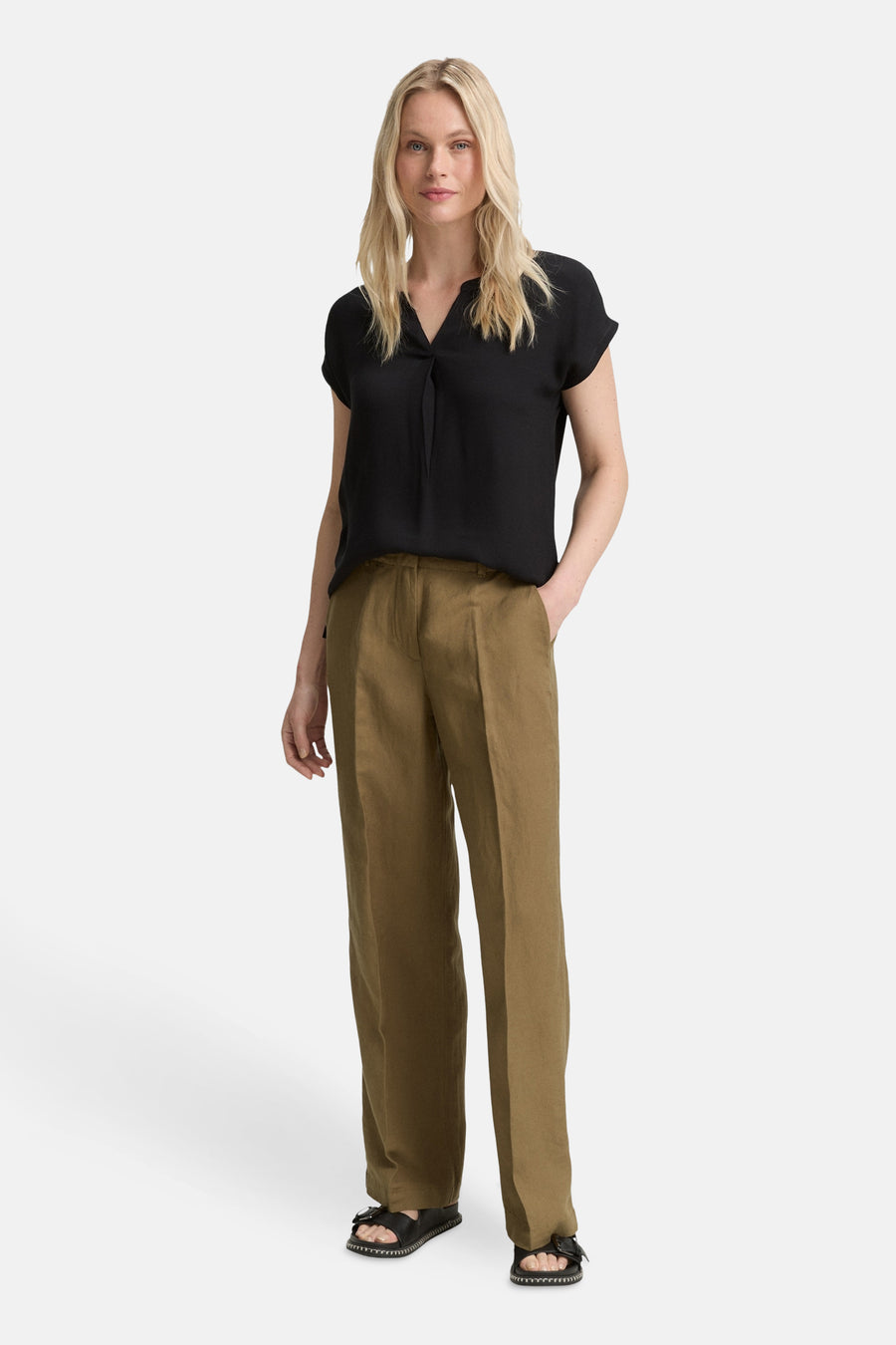 Pantalon kaki de Tom Tailor, coupe droite avec poches, porté avec un chemisier noir uni et des sandales.