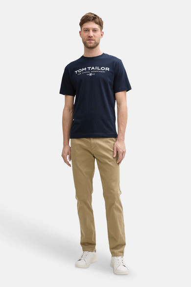 Navy blue short-sleeve T-shirt by Tom Tailor with white logo print, worn with khaki pants and white sneakers in full-length front view.