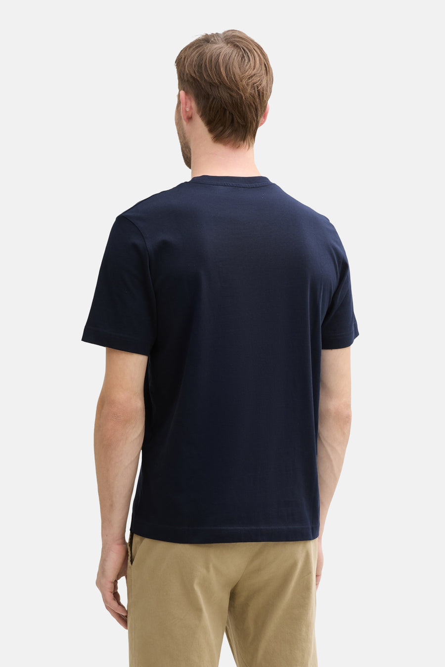 Navy blue short-sleeve t-shirt back view on model, plain cotton texture, paired with beige pants