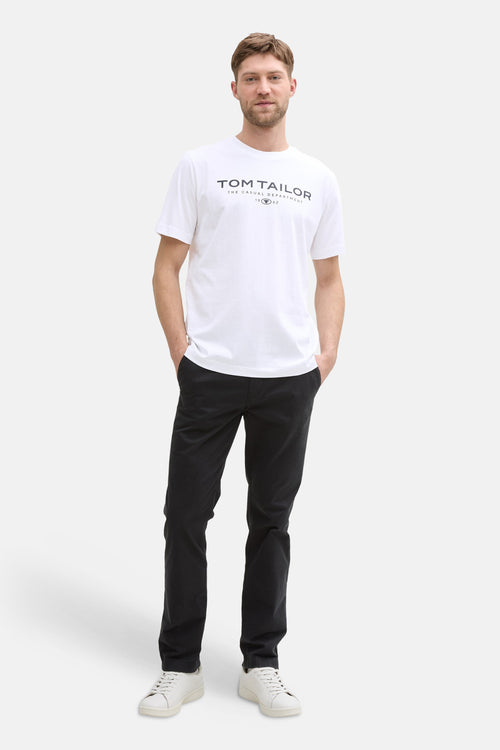 T-shirt blanc de Tom Tailor, porté avec un pantalon noir et des baskets blanches.
