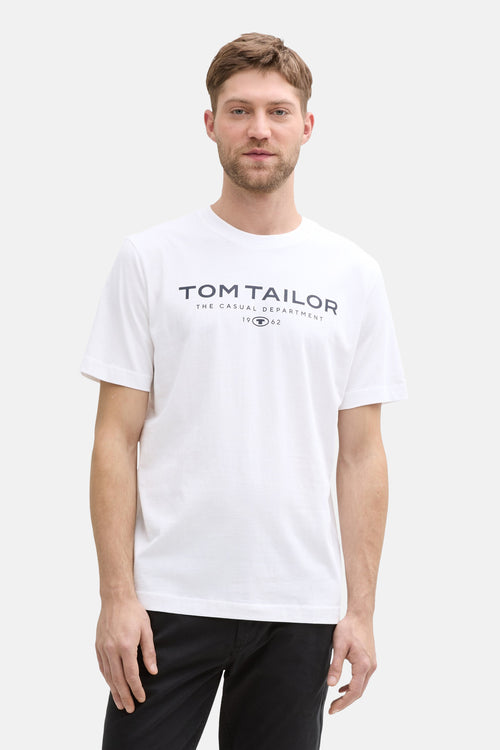 T-shirt blanc à manches courtes de Tom Tailor, avec imprimé graphique sur le devant, porté avec un pantalon noir.