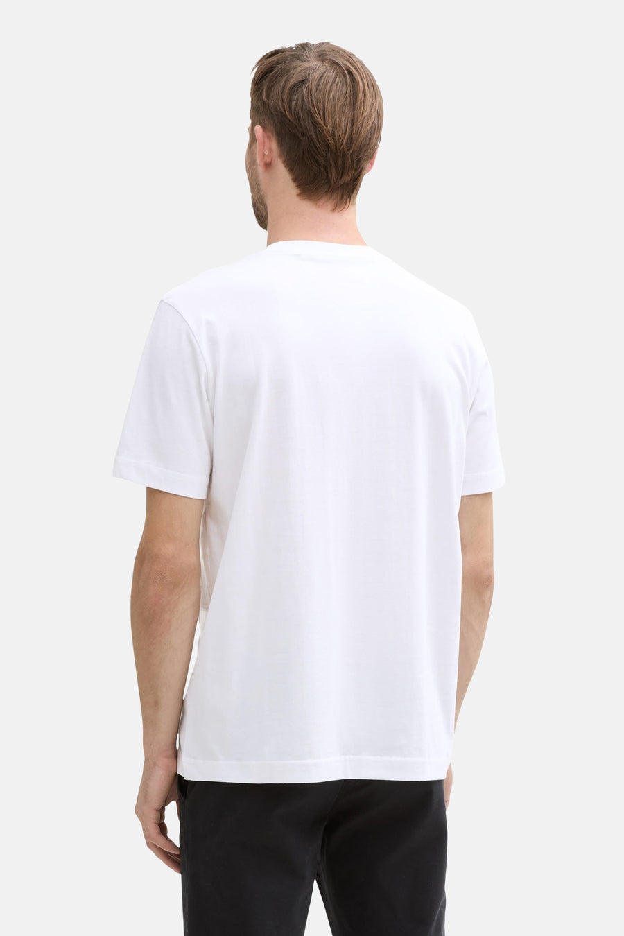 White short-sleeve t-shirt back view, plain cotton fabric, clean fit, model wearing black pants