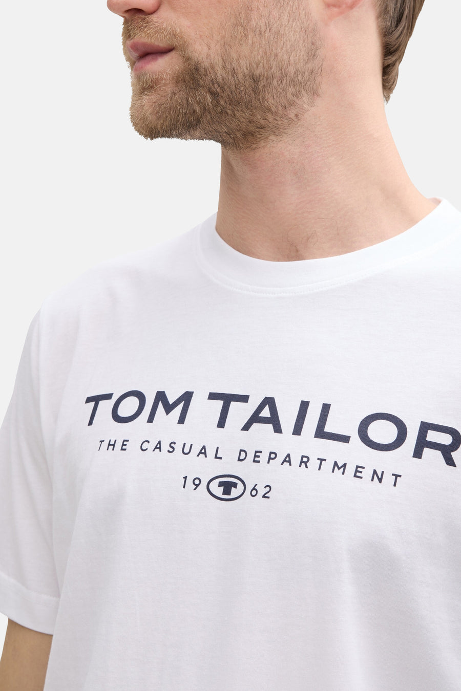 White short-sleeve T-shirt by Tom Tailor with navy logo print, crew neck, and front text design, shown in close-up side view.