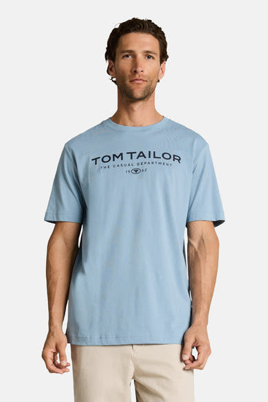 Lichtblauwe T-shirt van Tom Tailor, achtergezien op een man die een beige broek draagt.