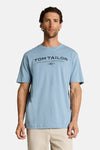 Lichtblauwe T-shirt van Tom Tailor, achtergezien op een man die een beige broek draagt.