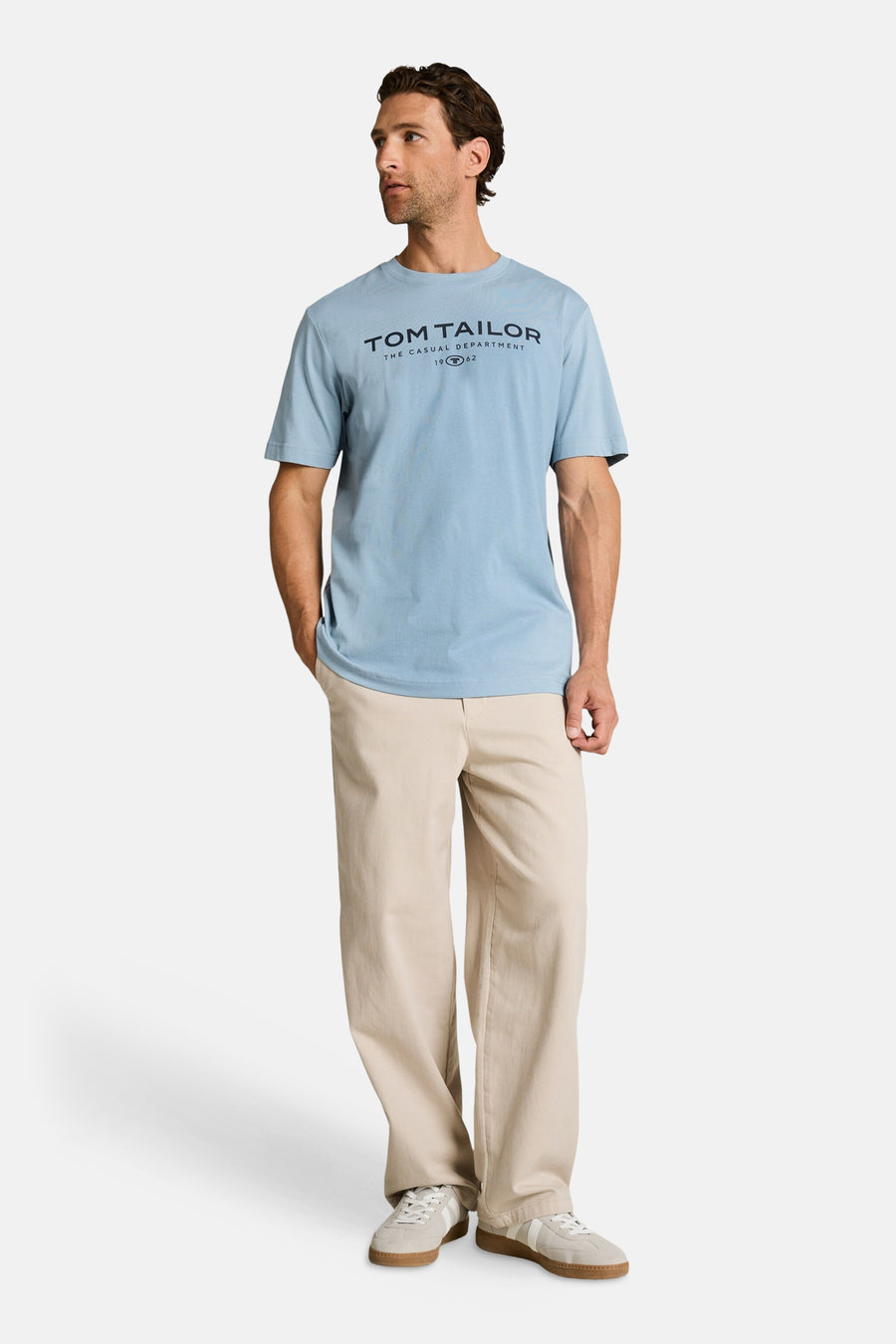 T-shirt bleu clair de Tom Tailor avec inscription, porté avec un pantalon beige et des baskets.