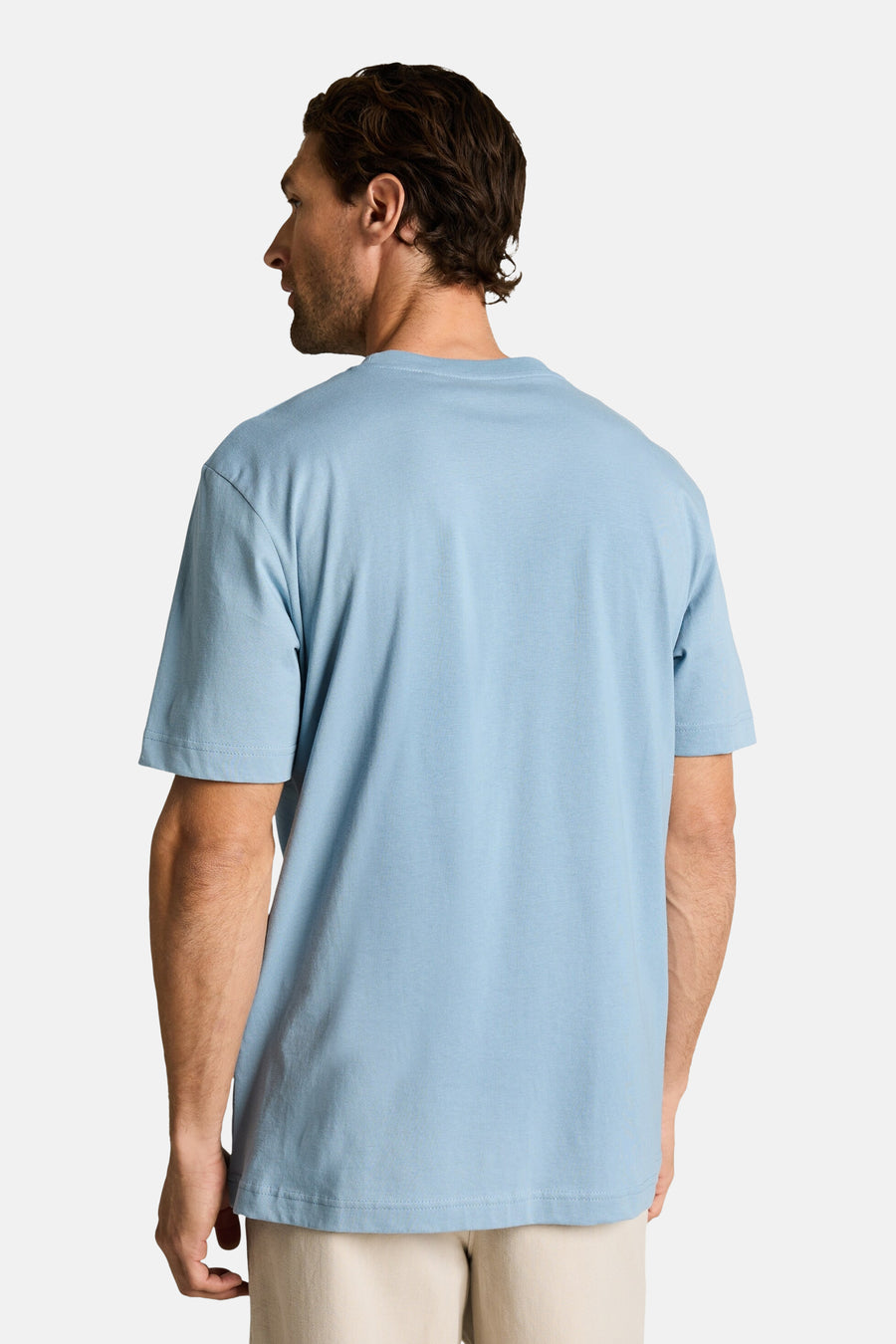T-shirt bleu clair de Tom Tailor, vue de dos sur un homme portant un pantalon beige.