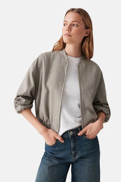 Veste courte beige de OPUS avec texture à chevrons portée sur un t-shirt blanc et un jean.