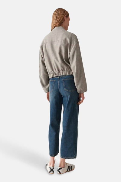 Veste courte beige d'OPUS, avec une texture tissée, portée avec un jean bleu et des baskets beiges.