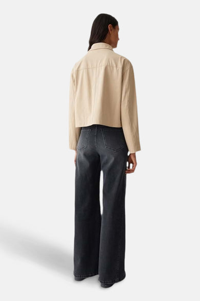 Veste courte beige d'OPUS, modèle ample avec des manches longues, portée avec un pantalon large gris.