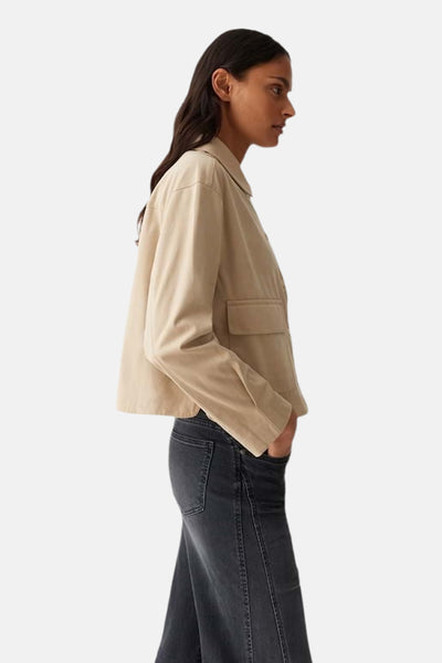Veste courte beige d'OPUS avec une poche plaquée, portée avec un pantalon taille haute.
