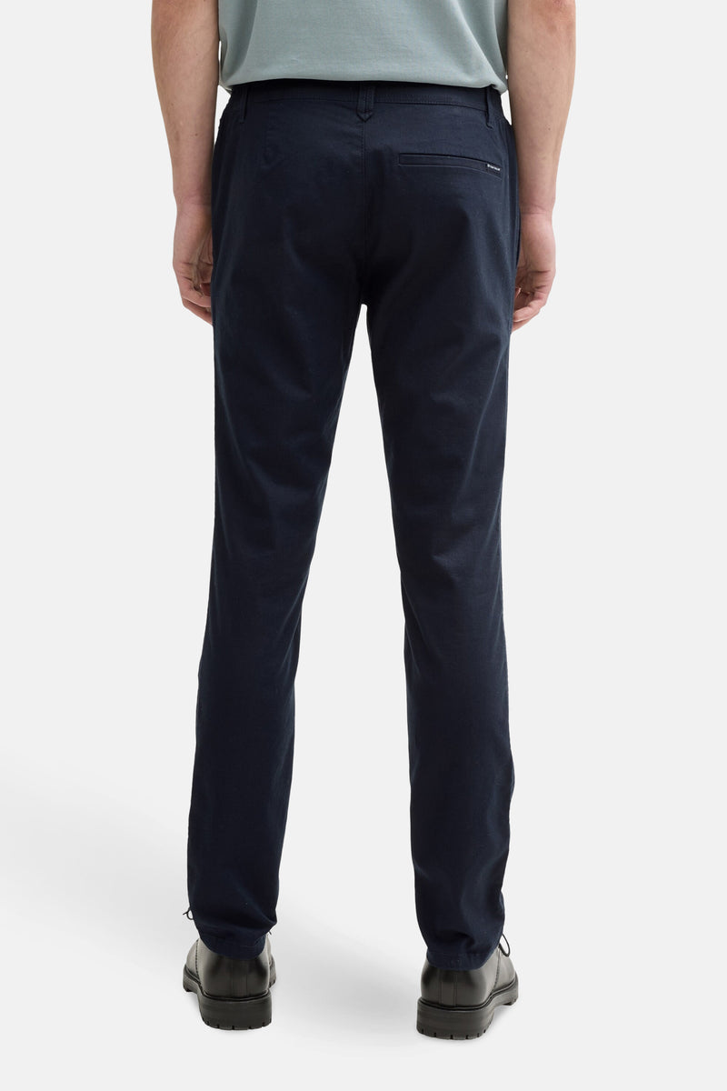 Marineblauwe chino van Tom Tailor, achterkant, gedragen met een lichtblauw T-shirt en zwarte schoenen.