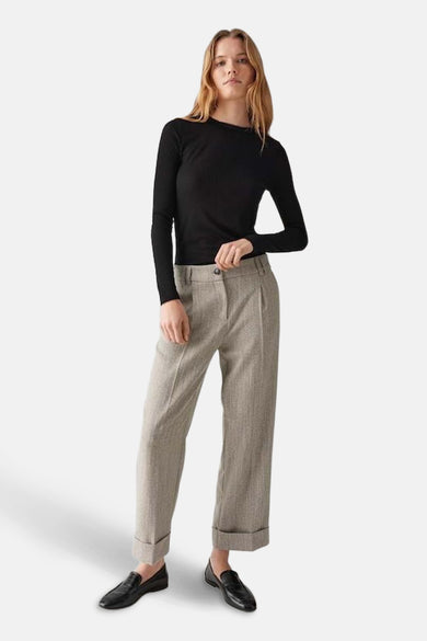 Pantalon de costume beige de OPUS avec des revers et une coupe décontractée, porté avec un haut noir et des chaussures noires.
