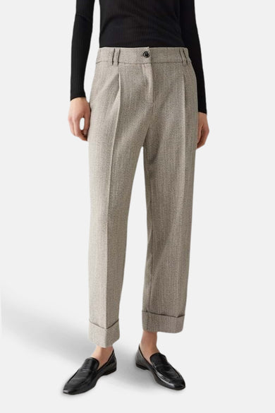 Pantalon de costume beige chiné de OPUS, à plis, avec ourlets retroussés et porté avec un haut noir uni.
