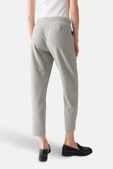Pantalon de costume gris par OPUS, vue de dos avec taille élastiquée et poches plaquées, porté avec des mocassins noirs.
