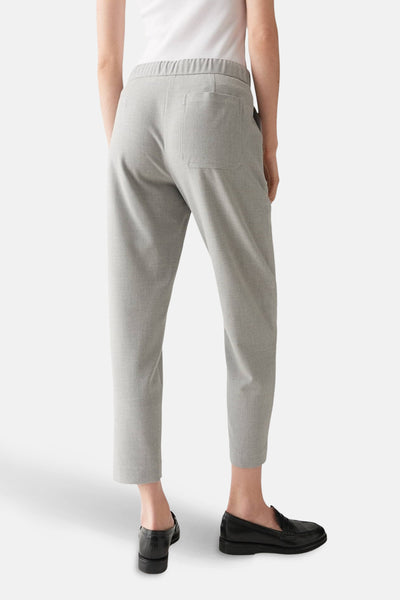 Pantalon de costume gris par OPUS, vue de dos avec taille élastiquée et poches plaquées, porté avec des mocassins noirs.
